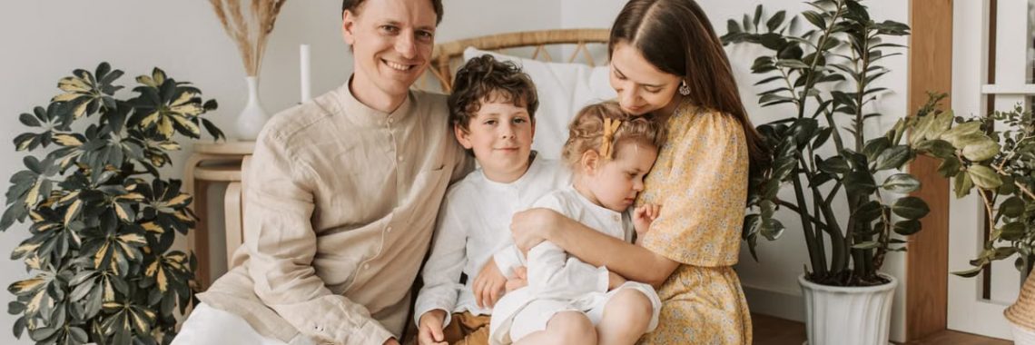 Happy family of four enjoying quality time together in a cozy, plant-filled room.